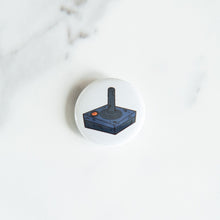 Load image into Gallery viewer, A button pin on a white tabletop. The button features an illustration of a retro Atari-like game controller.
