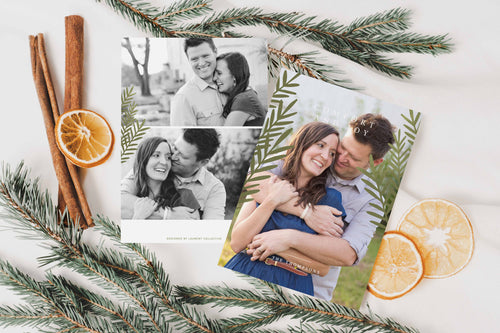 A photo of a double-sided Christmas card showing the front and back of the card laying on a white surface. Around the two sides of the card are pine needles, cinnamon sticks and dried oranges. The front of the card features a photo and the words “Comfort in Joy, The Thompsons” in white over the photo. The back of the card features two photos. 