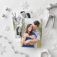 Load image into Gallery viewer, A photo of a double-sided Christmas card showing the front and back of the card laying on a white surface. Around the two sides of the card are white snowflake ornaments, silver bells, a silver reindeer, white tea light snowflake candle and silver star garland. The front of the card features a photo and the words “Comfort in Joy, The Thompsons” in white over the photo. The back of the card features two photos.