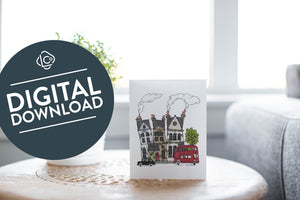 A greeting card laying on a wooden table with some cut wood details. The card features the a design with illustrated London houses, a black taxi cab and a red double decker bus. The words "digital download" are featured in a circle on top of the image. 