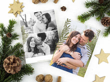 Load image into Gallery viewer, A photo of a two-sided Christmas card showing the front of the card on top of a brown wrapped gift on a white tabletop. Around the gift are pine needles, pinecones and wood star ornaments. The front of the card features a photo and the words “Comfort in Joy, The Thompsons” in white over the photo. The back of the card features two photos.