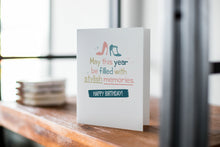 Load image into Gallery viewer, A card on a wood tabletop with an object in the background that is out of focus. The card features the words “May This Year be filled with stylish memories, Happy Birthday” with illustrated heels above the words. 