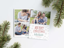 Load image into Gallery viewer, A photo of a Christmas card showing the front and back of the card laying on a white surface. Around the two sides of the card are pine needles. The front of the card features a photo on the top half of the card with the words “Merry Christmas” in a fun font with illustrated pine trees below the words. Below the pine trees you can customise with your family name. The back of the card features two photos along with illustrated snowflakes and pine trees.