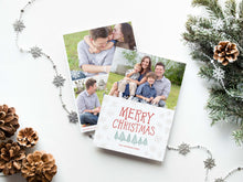 Load image into Gallery viewer, A photo of a double-sided Christmas card showing the front and back of the card laying on a white surface. Around the two sides of the card are Christmas items. The front of the card features a photo on the top half of the card with the words “Merry Christmas” in a fun font with illustrated pine trees below the words. Below the pine trees you can customise with your family name. The back of the card features two photos along with illustrated snowflakes and pine trees.