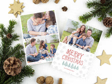 Load image into Gallery viewer, A photo of a two-sided Christmas card showing the front of the card on top of a brown wrapped gift on a white tabletop. Around the gift are pine needles, pinecones and wood star ornaments. The front of the card features a photo on the top half of the card with the words “Merry Christmas” in a fun font with illustrated pine trees below the words. Below the pine trees you can customise with your family name. The back of the card features two photos along with illustrated snowflakes and pine trees.
