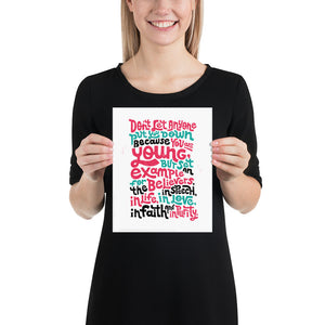 A woman holding a white art print. The print reads "Don't let anyone put you down because you are young, but set an example for the believers, in speech, in life, in love, in faith and in purity."