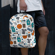 Load image into Gallery viewer, A boy standing in front of a black fence with just the waist down pictured. He is wearing a white short sleeve polo shirt with navy shorts. He’s holding a backpack in one hand by the top loop strap. The backpack has a white background with a basketball themed pattern backpack featuring illustrated basketballs, basketball jerseys, whistles, referee shirts, basketball hoops, stars, basketball shoes, fun play sketches and the word &quot;swish.&quot; The backpack straps are black. 