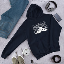Load image into Gallery viewer, A light navy hooded sweatshirt laying with jeans and shoes. The navy hoodie includes the phrase “Be Adventurous” in white with arrows pointing to the word “be” and a mountain illustration underneath the word “adventure.”