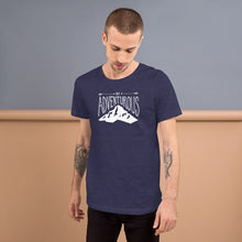 Load image into Gallery viewer, A man wearing a navy short sleeved t-shirt. The tee features the lettering and illustration in white. The phrase “Be adventurous” with arrows pointing to the word “be” and a mountain illustration underneath the word “adventure.”