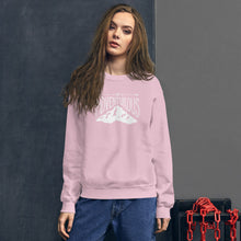 Load image into Gallery viewer, A woman wearing a light pink hoodie with lettering and illustration in white with the phrase “Be Adventurous” with arrows pointing to the word “be” and a mountain illustration underneath the word “adventure.”