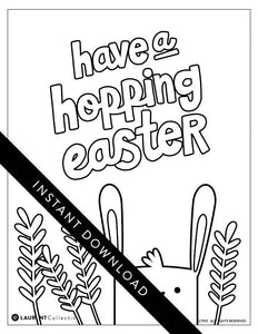 A coloring sheet on a white tabletop. There’s fake Easter grass around the color page. The card features an illustrated Easter bunny with some leaves around the bunny. The words “have a hopping Easter” are above the bunny. 