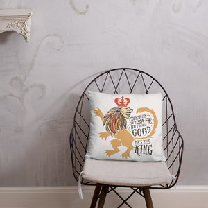 A white square pillow with artwork on it on a wire shirt. The artwork features hand drawn illustration of the Chronicles of Narnia lion character Aslan. Inside the illustration there is the quote "Course He Isn't Safe, But He's Good. He's the King."