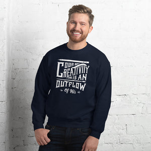 A man wearing a navy sweatshirt featuring hand drawn lettering in white with the words "Our creativity is an outflow of His."
