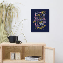 Load image into Gallery viewer, A canvas shown on a wall above a shelf. The canvas is purple and features hand drawn text in white, pink and yellow reading &quot;May the God of hope fill you with all joy and peace as you trust him, so that you may overflow with hope by the power of the holy spirit.&quot; 
