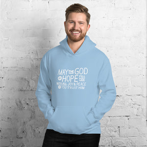 A man wearing a light blue hoodie featuring hand drawn lettering in white with the words "May the God of hope fill you with all joy and peace as you trust him."