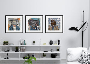 Three black framed prints hanging on a wall above a shelf. The artwork in the frames are three different vintage radios featured as "heads" on a person.