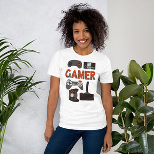 A woman wearing a white short sleeved t-shirt. The tee features hand drawn lettering and illustrations featuring different game controllers and the word "gamer." The illustrations and gamer word are in red, grey and black. 