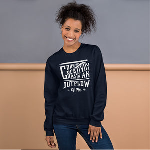 A woman wearing a navy sweatshirt featuring hand drawn lettering in white with the words "Our creativity is an outflow of His."