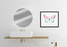 Load image into Gallery viewer, Artwork in a black frame featured in a bathroom next to a circle mirror and above a sink. The hand drawn artwork features the scripture verse &quot;Therefore, if anyone is in Christ, the new creation has come. The old has gone. The new is here.&quot; The words are featured inside a butterfly. 