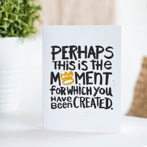 A greeting card standing on a table top. The card reads 'Perhaps this is the moment for which you have been created'.