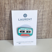 Load image into Gallery viewer, An enamel pin featuring the words &quot;good vibes&quot; inside an illustrated cassette tape. The pin is on the Laurent Collective backing it comes on when you order the pin.