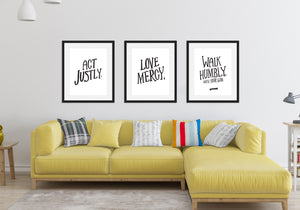 Three black frames featured above a yellow sofa in a living room. The first frame features artwork saying "Act Justly." The second frame says "Love Mercy." The third frames says "Walk Humbly, with your God - Micah 6:8."