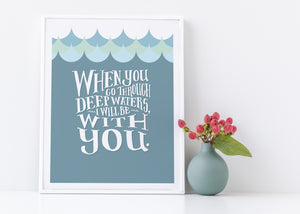 Artwork in a white frame with the with a white matte. The frame is leaning on a white counter. The artwork features hand drawn lettering reading "When you go through deep waters, I will be with you."