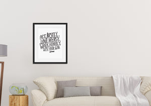Lettering artwork is featured in a black frame above a sofa. The artwork features hand drawn lettering reading "Act Justly, Love Mercy, Walk Humbly with your God" - Micah 6:8.