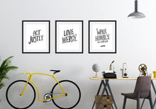 Load image into Gallery viewer, Three black frames featured above a desk with a bicycle off to the side of the desk. The first frame features artwork saying &quot;Act Justly.&quot; The second frame says &quot;Love Mercy.&quot; The third frames says &quot;Walk Humbly, with your God - Micah 6:8.&quot;