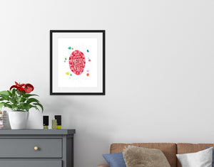 Lettering artwork is featured in a black frame above a sofa. The artwork features an illustrated jewel with the words inside "You are more precious than jewels." There is a scattering of illustrated, colored jewels around the image. 