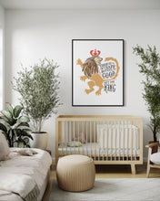 Load image into Gallery viewer, Artwork in a black frame with the with a white matte. The frame is hanging on a wall in a nursery above a crib. The artwork features an illustrated with the words &quot;Course He Isn&#39;t Safe, But He&#39;s Good. He&#39;s the King.&quot;