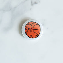 Load image into Gallery viewer, A buttons on a white tabletop. The button features an illustrations of a basketball. 