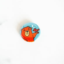 Load image into Gallery viewer, A button pin on a white tabletop. The button design features an illustrated bear. 