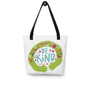 A white tote bag with black handles on a white background. The bag features a design with the words 'be kind' with illustrated hugging hands around the words. 