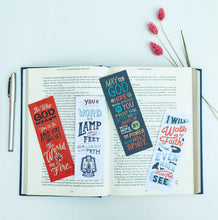 Load image into Gallery viewer, A set of four bookmarks laying across an open Bible. There are a pen off to the left hand side and dried flowers across the upper righthand corner. 