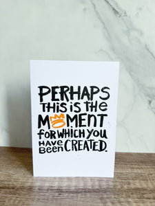 A greeting card standing on a table top. The card reads 'Perhaps this is the moment for which you have been created'.