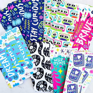 A image of seven bookmarks featuring illustrated word designs with the words dream, good vibes, i love books, wild and free, stay curious, and brave. 