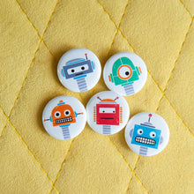 Load image into Gallery viewer, A set of five button pins on a yellow background. The buttons feature five different illustrations of robots.