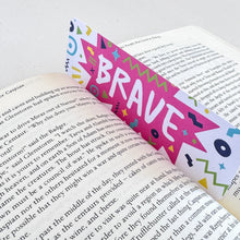 Load image into Gallery viewer, A close up of a bookmark featuring the word &quot;brave&quot; with a pink star like illustration behind the word.