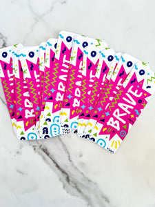 Bookmarks with the word "brave" in white within a star-like pink shape with fun, sketchy elemts around. 