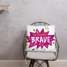 Load image into Gallery viewer, A pillow on a chair against a grey wall. The white pillow features the artwork on a white background with a hot pink star with the word &#39;brave&#39; inside and sketchy, fun elements around the word. 