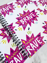 Load image into Gallery viewer, A closeup of three spiral notebooks are on a tabletop. The white spiral notebooks have black spiral binding. The pattern design features the word &quot;brave&quot; inside a hot pink star with sketchy elements around. 