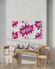 Load image into Gallery viewer, A large flag featured in a kids playroom above a kids table. The white flag features a pattern with the word &quot;brave&quot; featured inside a pink star-like shape with sketchy illustrations around the word. 