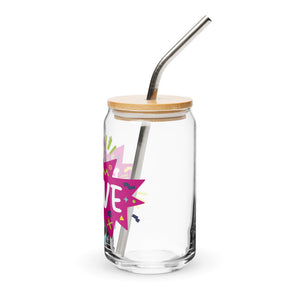 A photo of a glass can tumbler on a white background showing the side of the glass. The glass tumbler has a bamboo lid and silver metal straw. The design on the glass tumbler says the word "brave" inside a hot pink star with illustrated sketchy elements around the word. 