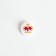 Load image into Gallery viewer, A button on white tabletop. The button features an illustration of a royal crown. 