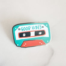 Load image into Gallery viewer, An enamel pin featuring the words &quot;good vibes&quot; inside an illustrated cassette tape.