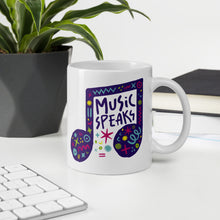 Load image into Gallery viewer, A white mug on a desktop. The mug features a design with the words &#39;music speaks&#39; in an illustrated musical note with sketchy elements around it. 