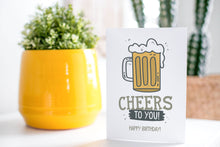 Load image into Gallery viewer, A greeting card is on a table top with a yellow plant pot and a green plant inside. The card features the words “Cheers to You! Happy Birthday!” with an illustrated beer mug.