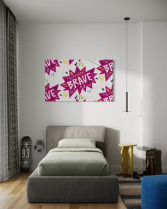 A large flag featured in a teen's bedroom above the bed. The white flag features a pattern with the word "brave" featured inside a pink star-like shape with sketchy illustrations around the word. 