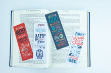 Load image into Gallery viewer, A set of four bookmarks laying across an open Bible. The Bible is on a white tabletop. 